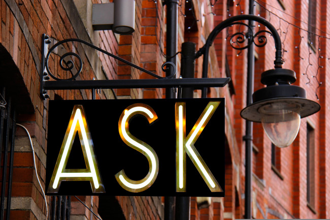 Auf einem Schild steht "ASK". - Das englische Wort "ask" kann mit "fragen" übersetzt werden..